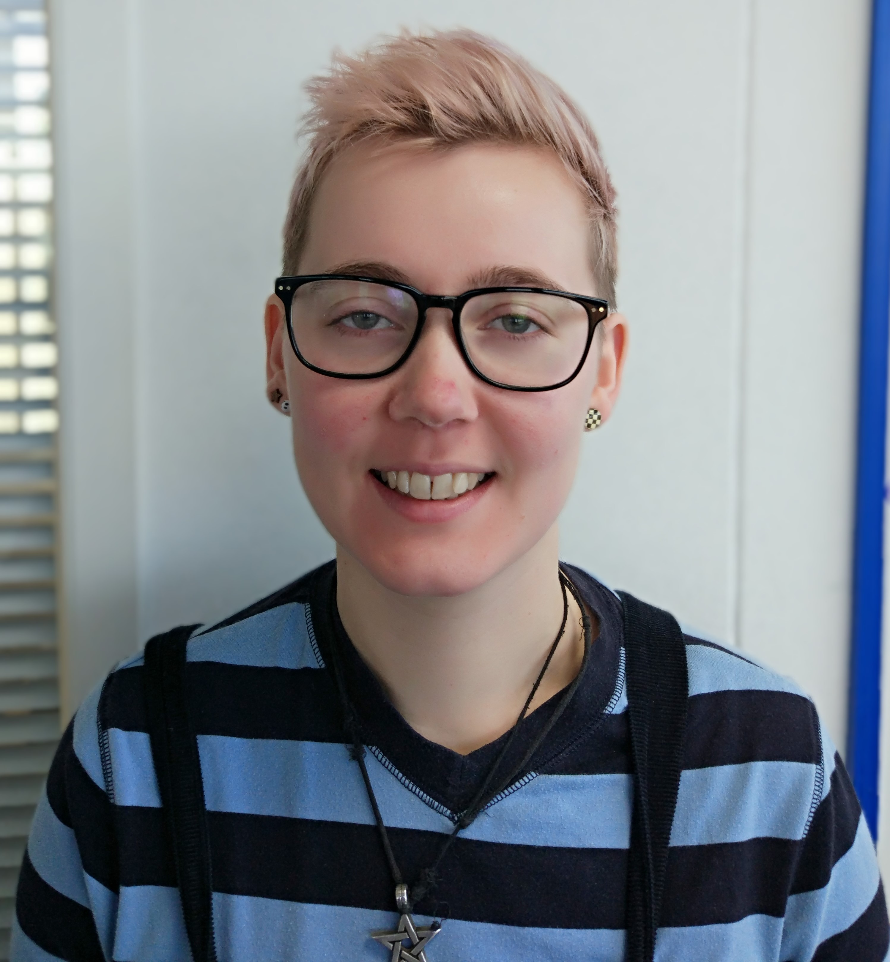 Photo of Jo wearing a striped top and geeky glasses.